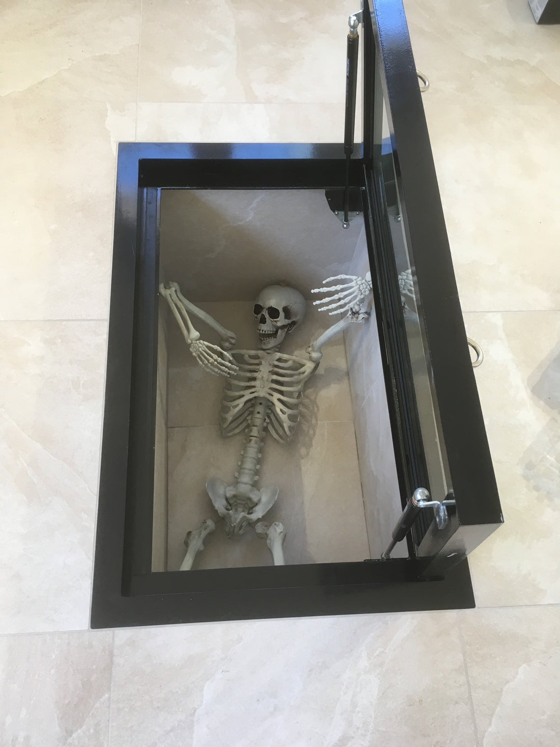 A walk-on glass floor hatch in a living room, acting as a display Halloween themes basement below.