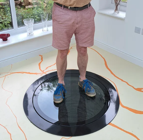 Person standing on a transparent non-slip glass well cover by Glass Floor Systems, showcasing safe, clear design for basement access.