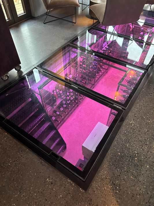 Hinged glass wine cellar door with fixed panels by Glass Floor Systems Ltd, designed for extra-large wine cellar access.